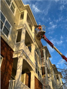 A Terra Pro-Wash worker on a lift pressure washing an apartment building