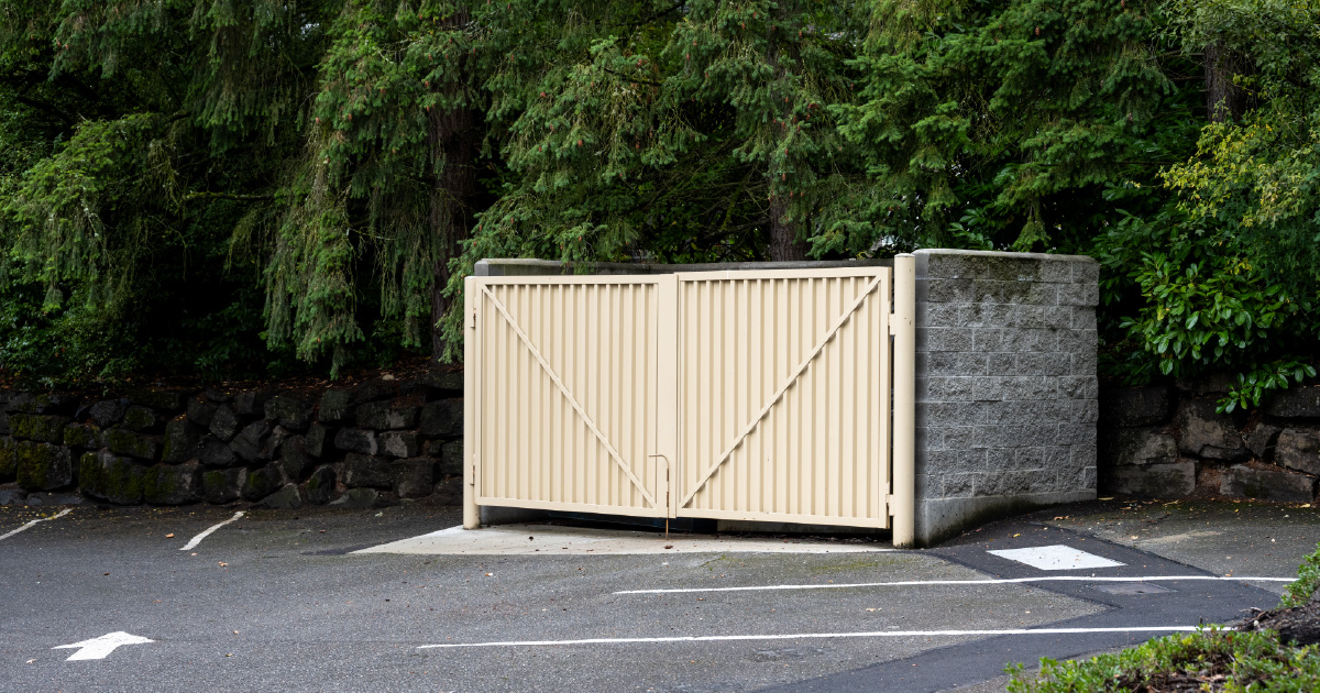 A commercial dumpster enclosure with a metal gate