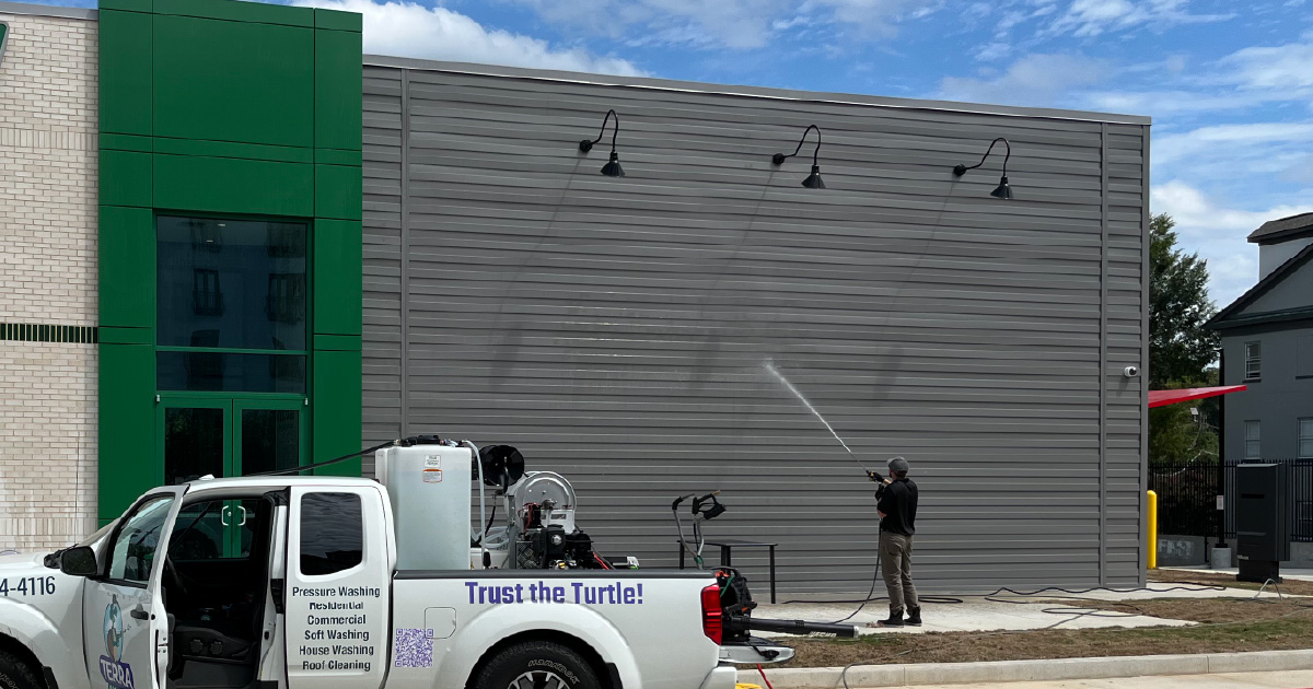 A pressure washing specialist from Terra CPS cleaning a commercial building
